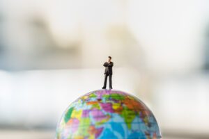 Property investor model standing on top of a globe to represent overseas real estate investment