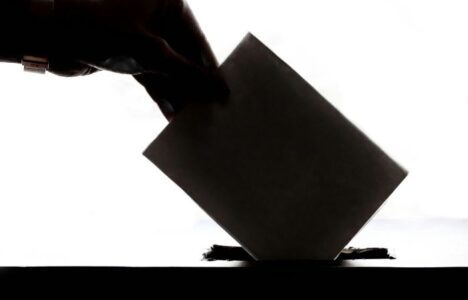 hand putting a voting slip into a ballot box