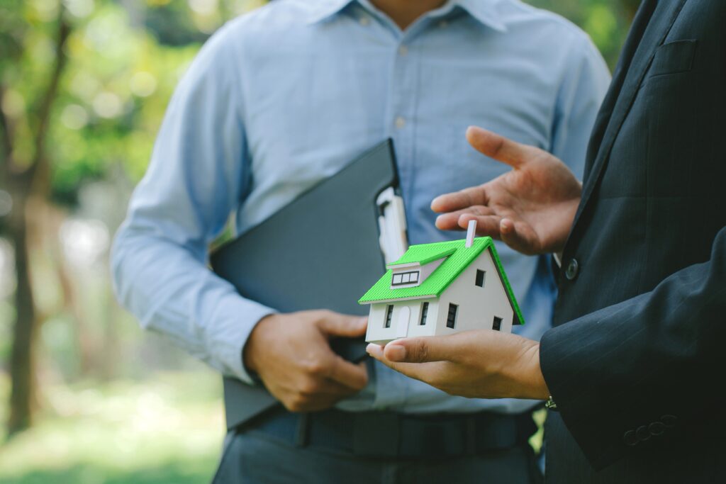 Businessmen holding a model of an eco-friendly house with green roof
