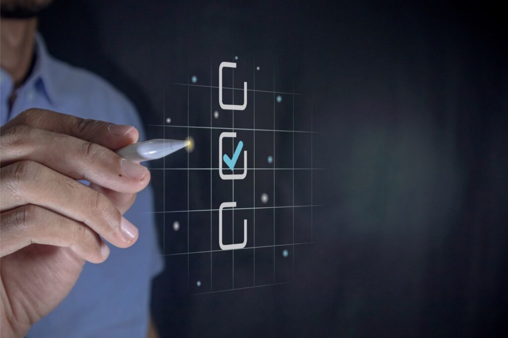 Hand holding a pen ticking a blue checkmark on a box on virtual screen