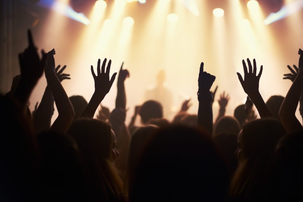 Live music event with shadows of people's arms up in the crowd